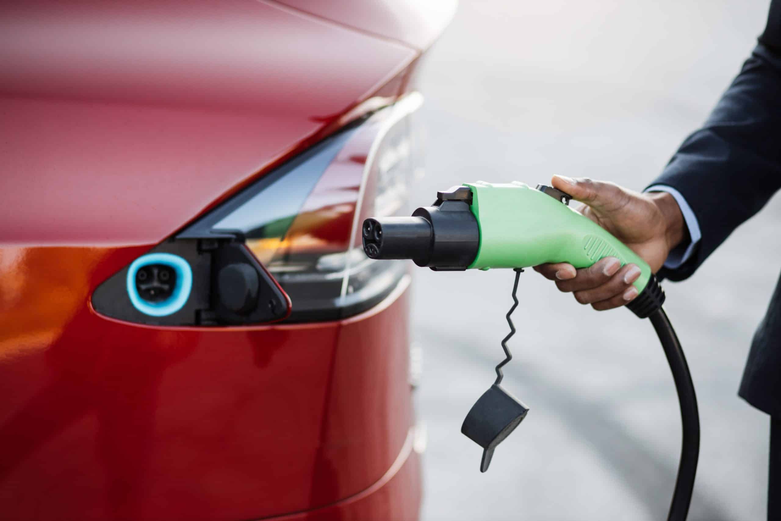 close up of male hand holding green electric charging plug