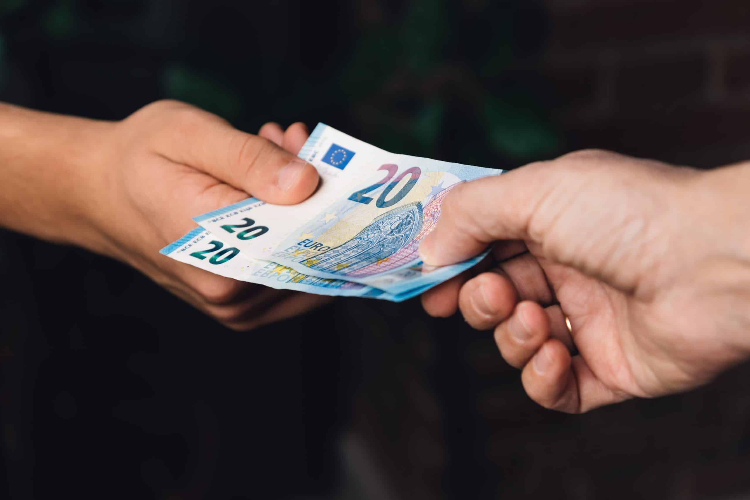 hand of woman is giving euro money to a young man