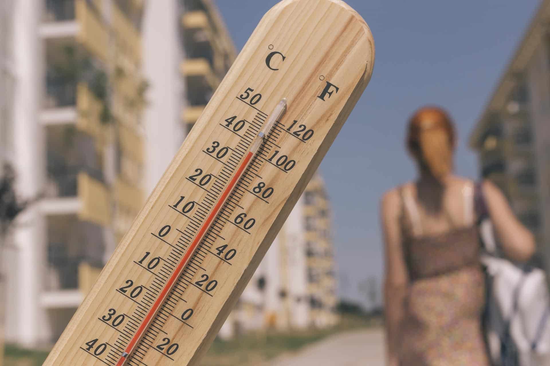 thermometer with one hundred degree fahrenheit in the city on hot sunny summer day